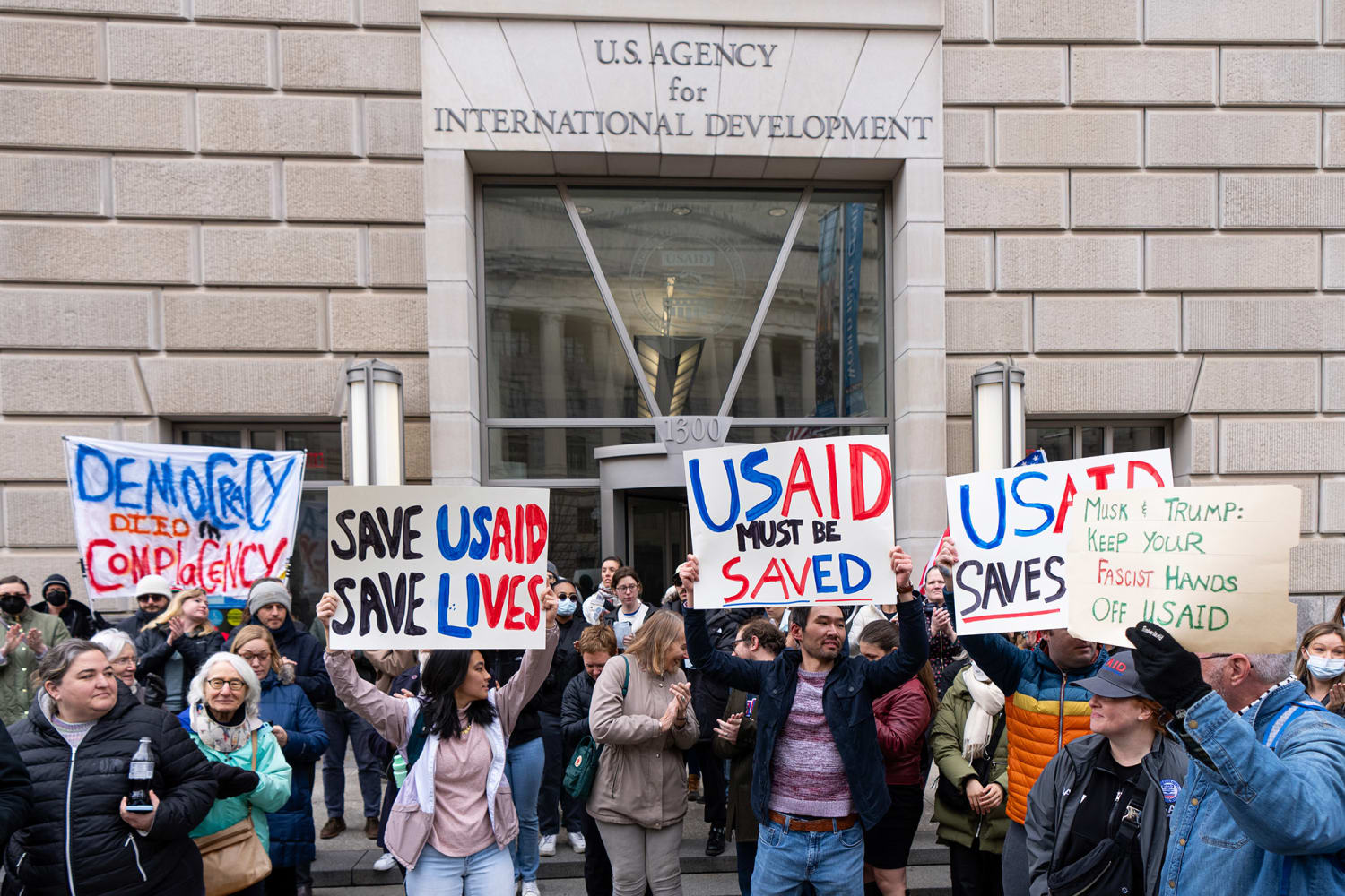 Photo of people holding placards standing in front of USAID Office in Washington DC